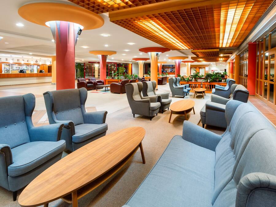 A spacious lobby with modern seating arrangements, including sofas and armchairs, and a wooden coffee table.