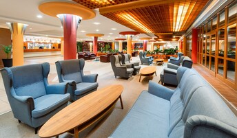 Un vestíbulo espacioso con modernas zonas de estar, que incluyen sofás y sillones, y una mesa de centro de madera.