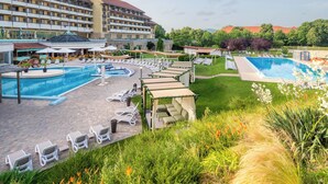Un hotel con un amplio espacio de piscina, numerosas tumbonas y un jardín bien cuidado.
