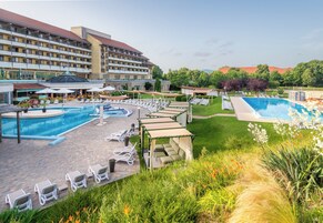 Un hotel con un amplio espacio de piscina, numerosas tumbonas y un jardín bien cuidado.