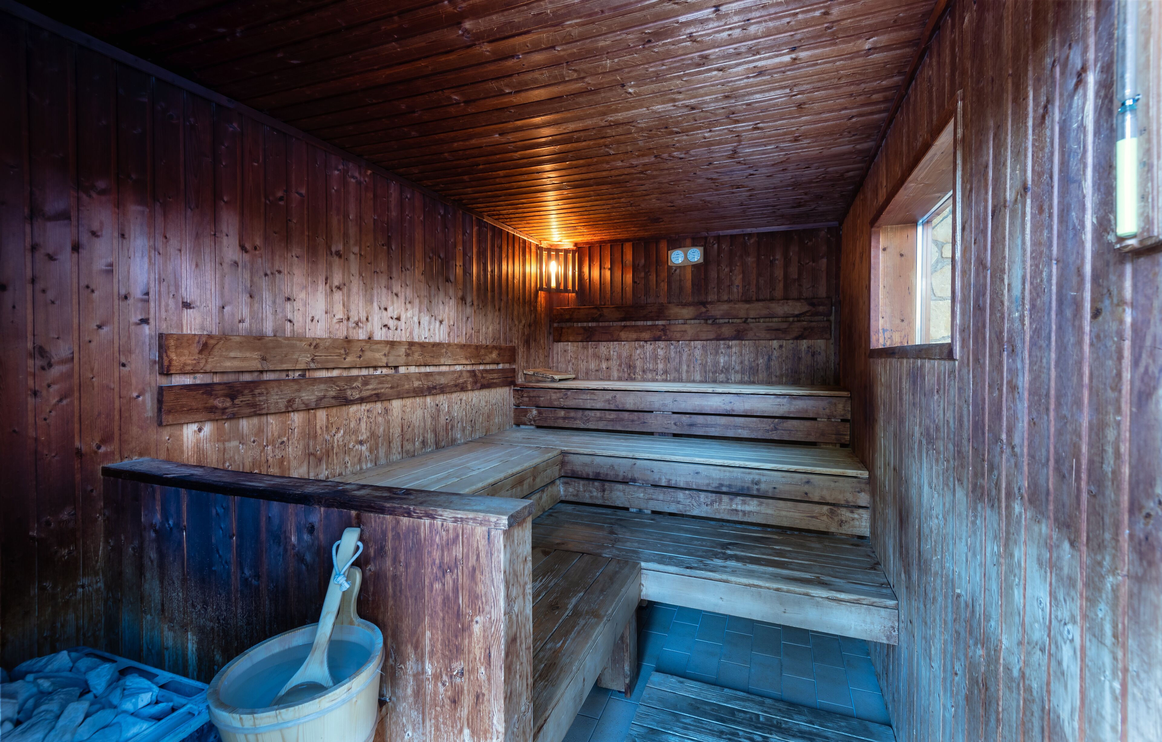 A wooden sauna with benches and a wooden bucket.