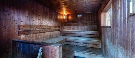 A wooden sauna with benches and a wooden bucket.