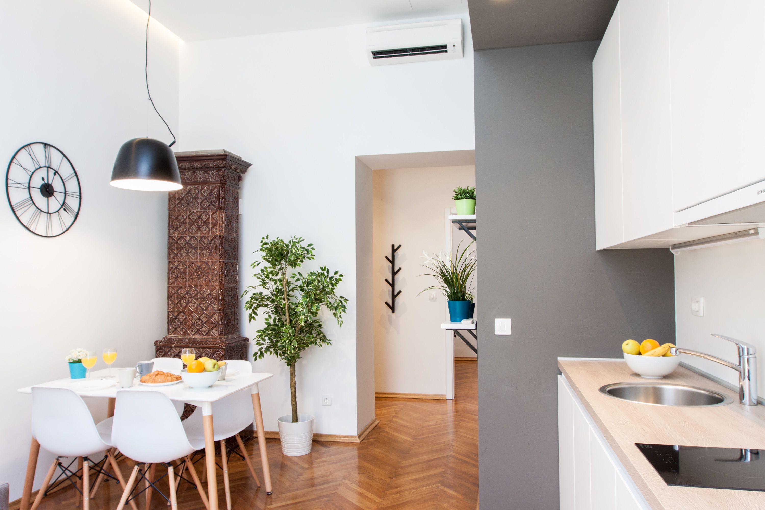 A modern kitchen with a sink, countertop, and a dining area with chairs and a table.
