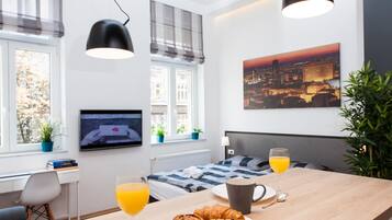 Quarto de hotel moderno com cama, mesa de café da manhã e uma pintura com vista para a cidade.