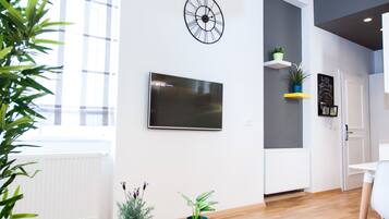 Un interior moderno con un televisor de pantalla plana grande, un reloj de pared y plantas en macetas.