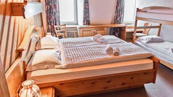 Ein Zimmer mit einem Holzbett mit Etagen, einem Schreibtisch, einem Stuhl, einem Heizkörper und einem Fenster mit Vorhängen.