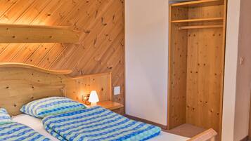 Une chambre à coucher avec une tête de lit en bois, un lit recouvert d’une literie à motifs bleus, une lampe de chevet et une armoire en bois.