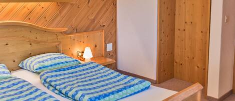 Una camera da letto con una testiera in legno, un letto con biancheria azzurra a motivi decorativi, una lampada da comodino e un'armadio in legno.