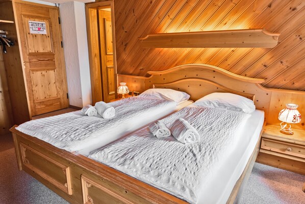 Una cama de madera con dos almohadas y una mesita de noche con una lámpara.