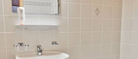 A bathroom with a white sink, mirror, and bathtub.