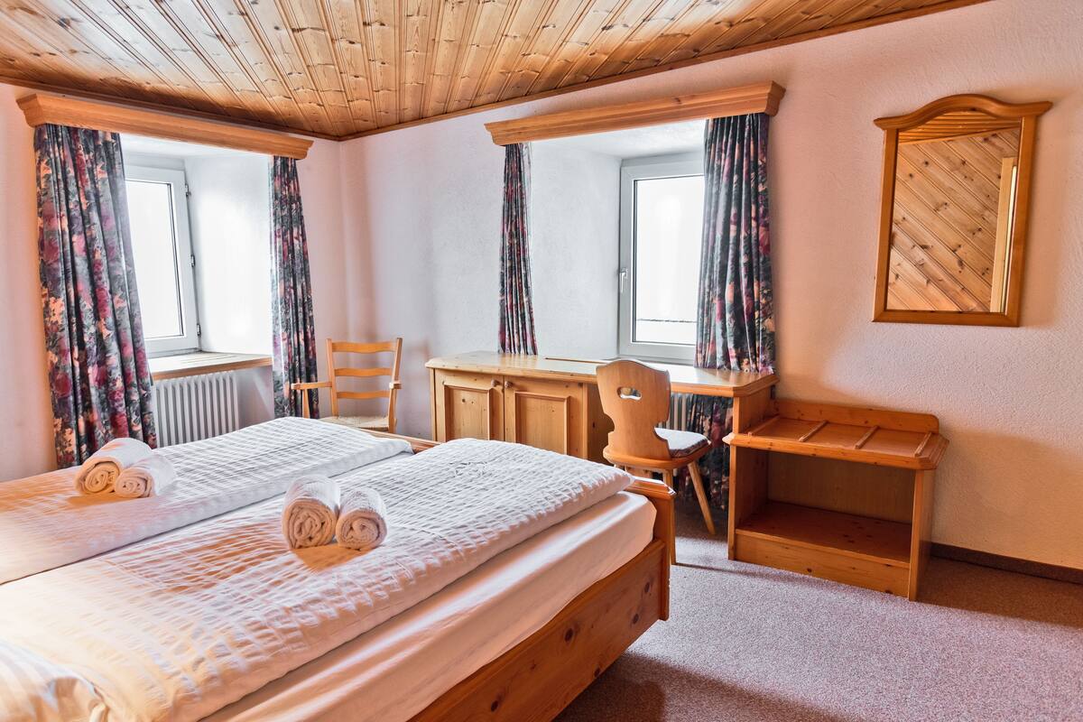 Un dormitorio con dos camas, muebles de madera, un escritorio y una silla.