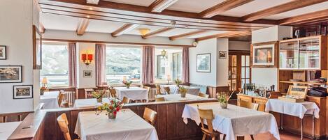 Un restaurante con vigas de madera, manteles blancos y vistas a la montaña.