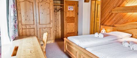 Una habitación de madera con una cama, un escritorio y un armario.