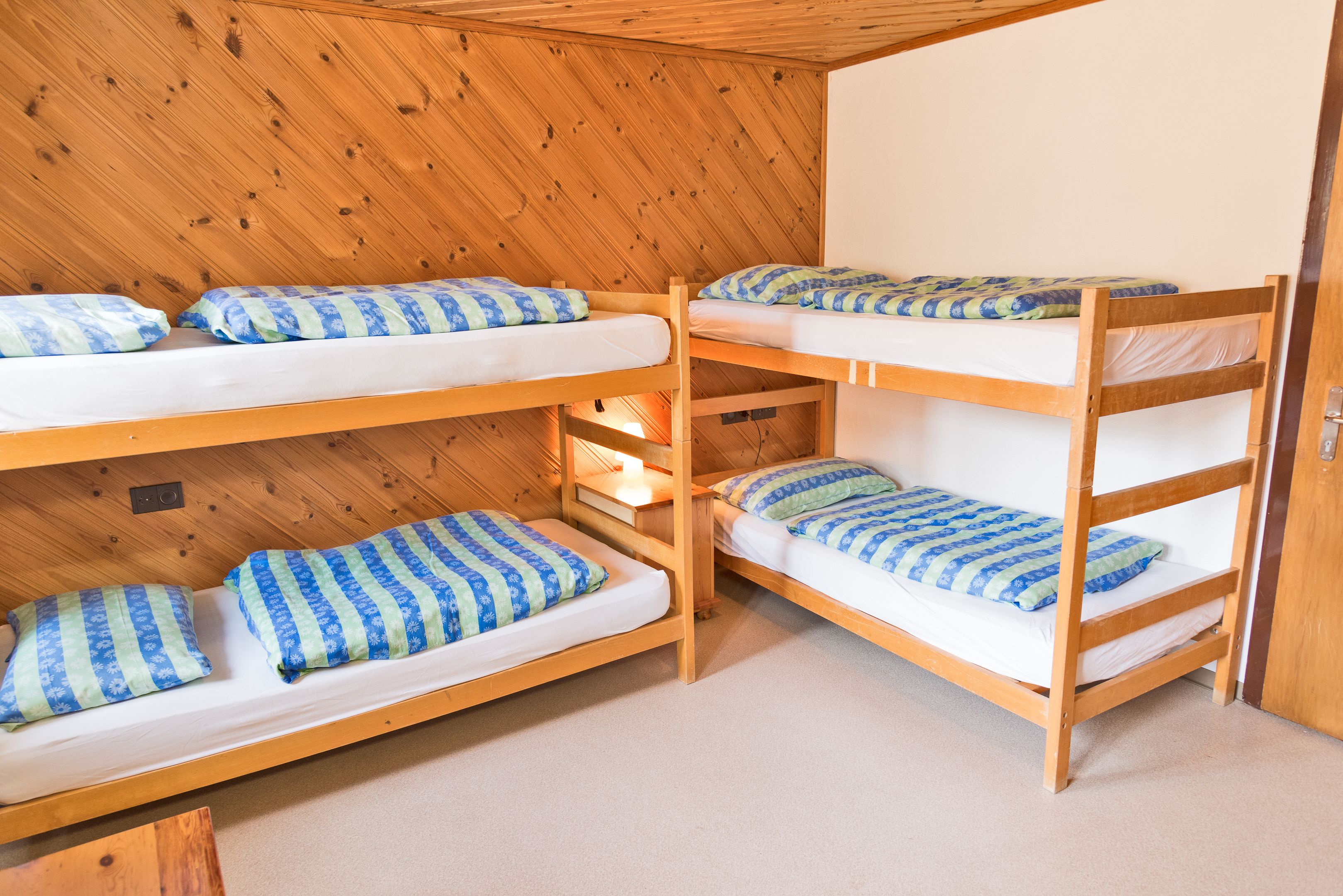 A bunk bed room with wooden walls and a carpeted floor.