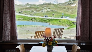 Une table dressée pour deux personnes, avec vue sur un lac, une route et un pylône de ligne électrique.