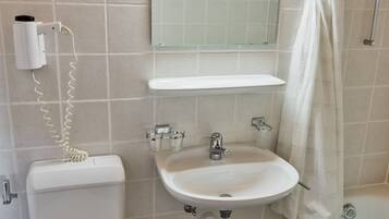 Une salle de bain comprenant des toilettes, un lavabo et un espace douche.