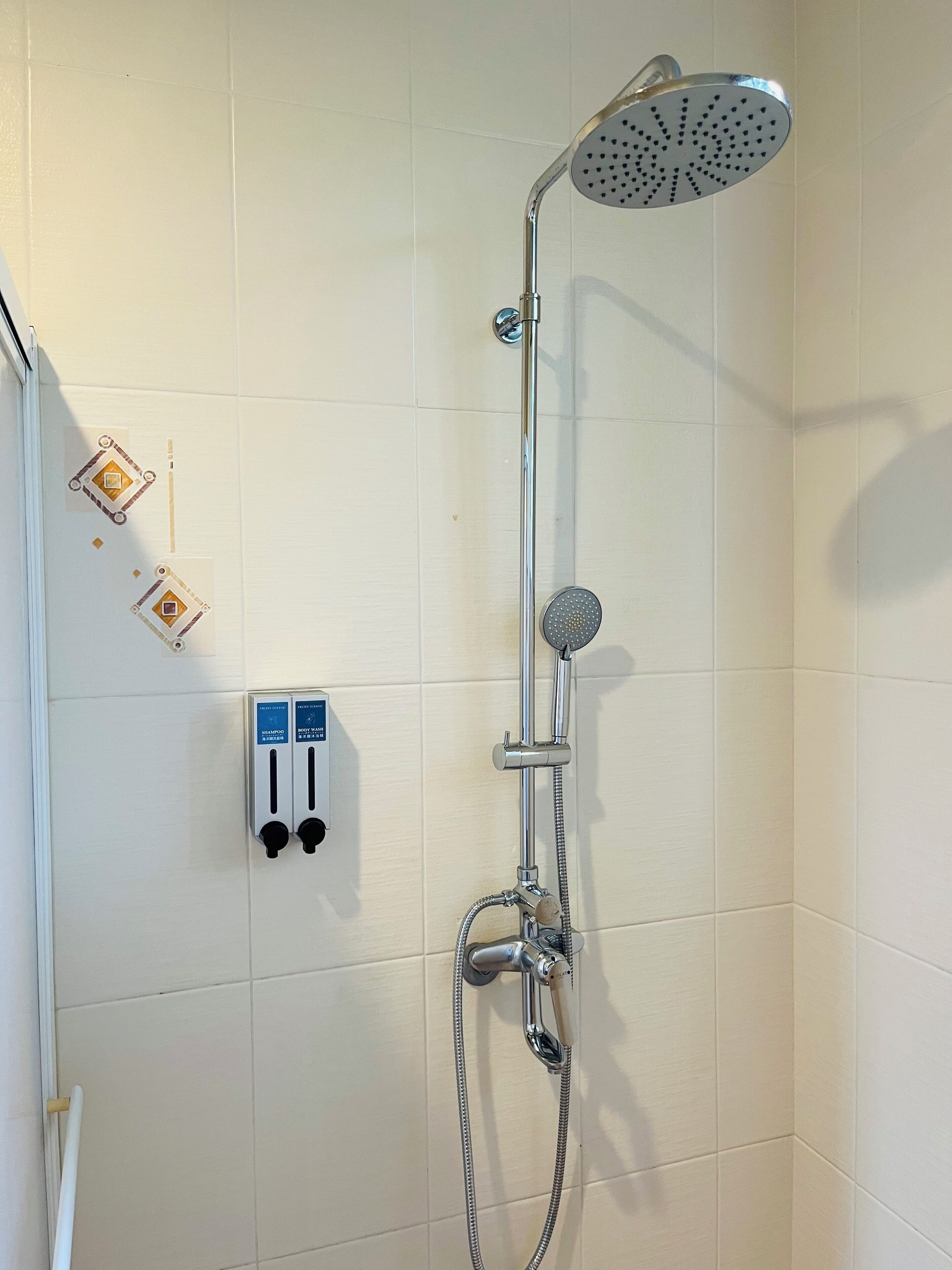 A shower with a handheld showerhead and a wall-mounted control panel.