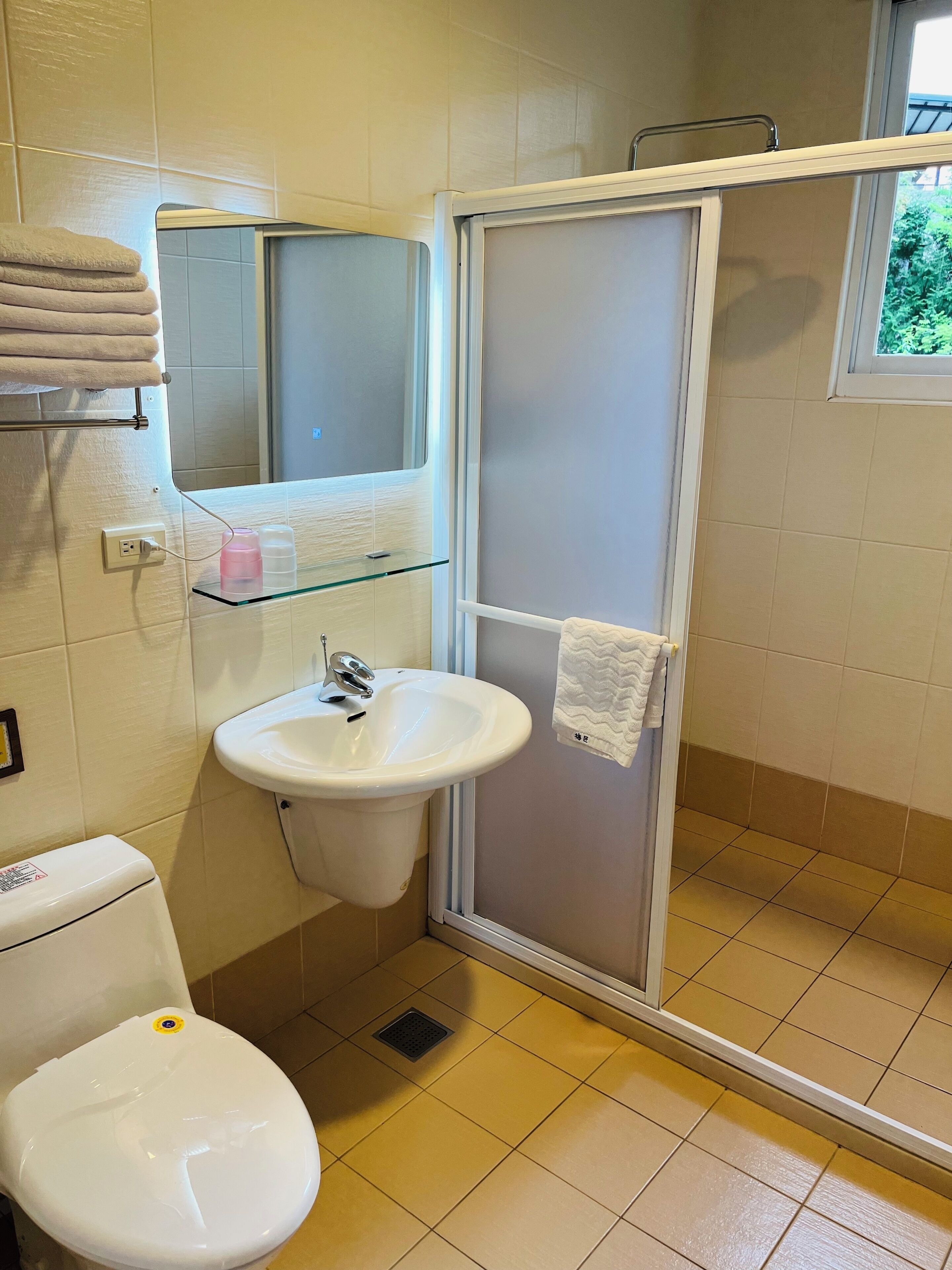 A bathroom with a toilet, sink, and glass shower enclosure.