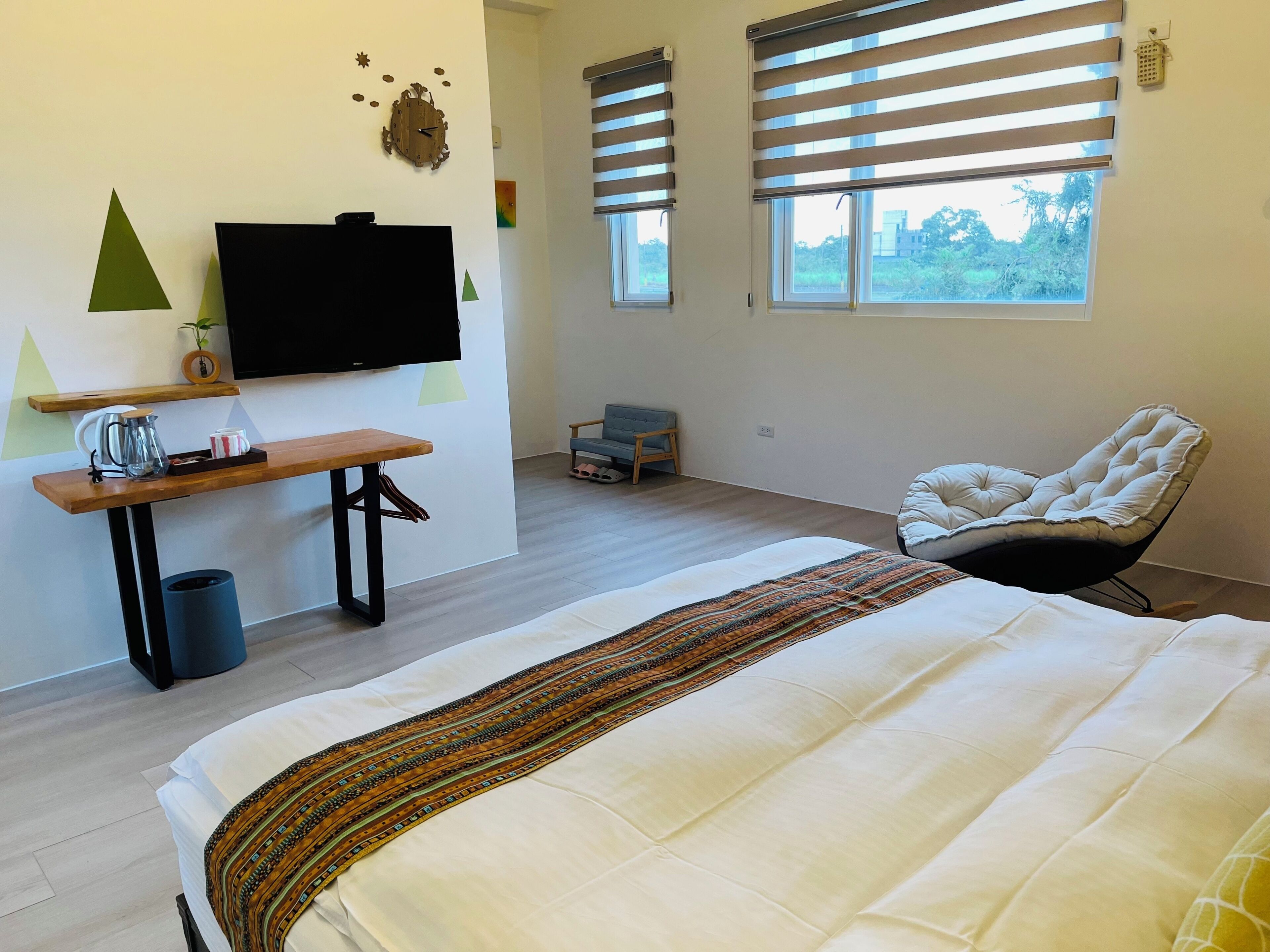 A bedroom with a bed, a TV, a chair, a window, and a small table.