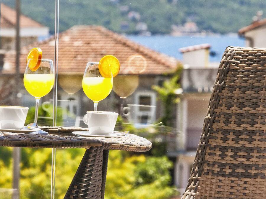 A wicker chair and table with two glasses of orange juice and white cups.