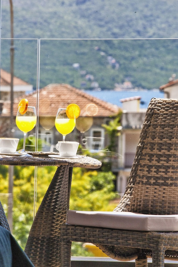 A wicker chair and table with two glasses of orange juice and white cups. - Hotel ACD Wellness & Spa (Herceg Novi)