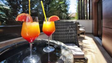 Two drinks on a glass table with a wicker chair in the background.