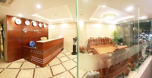 A reception area with a wooden reception desk, a clock, and a seating area with chairs and a table.