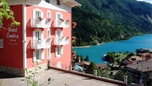 A hotel building with balconies overlooking a lake and mountains. - Hotel Londra (Molveno)