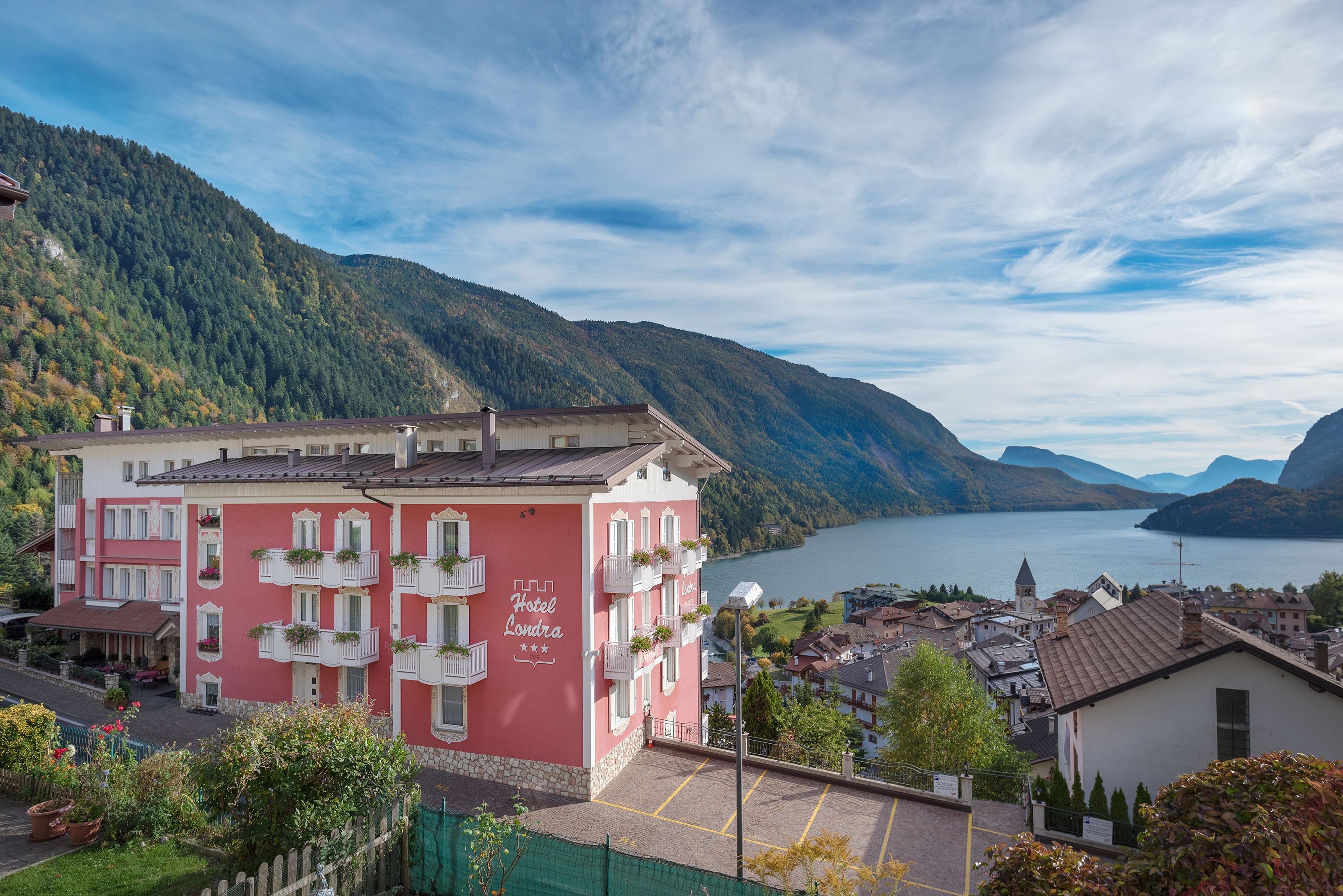 Un bâtiment rose doté de balcons, offrant une vue sur un lac et des montagnes.