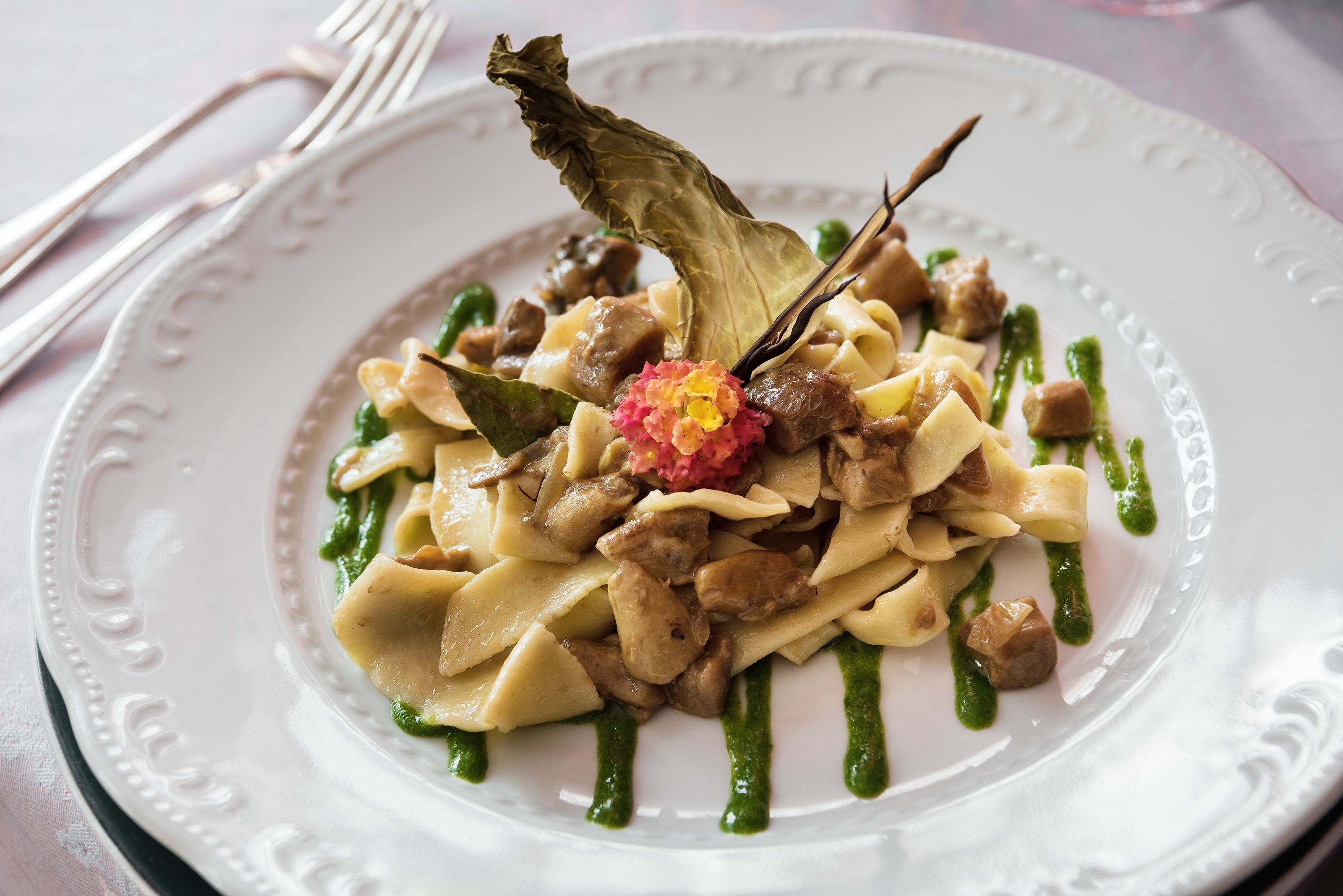 Prato de massa com carne e uma flor decorativa.