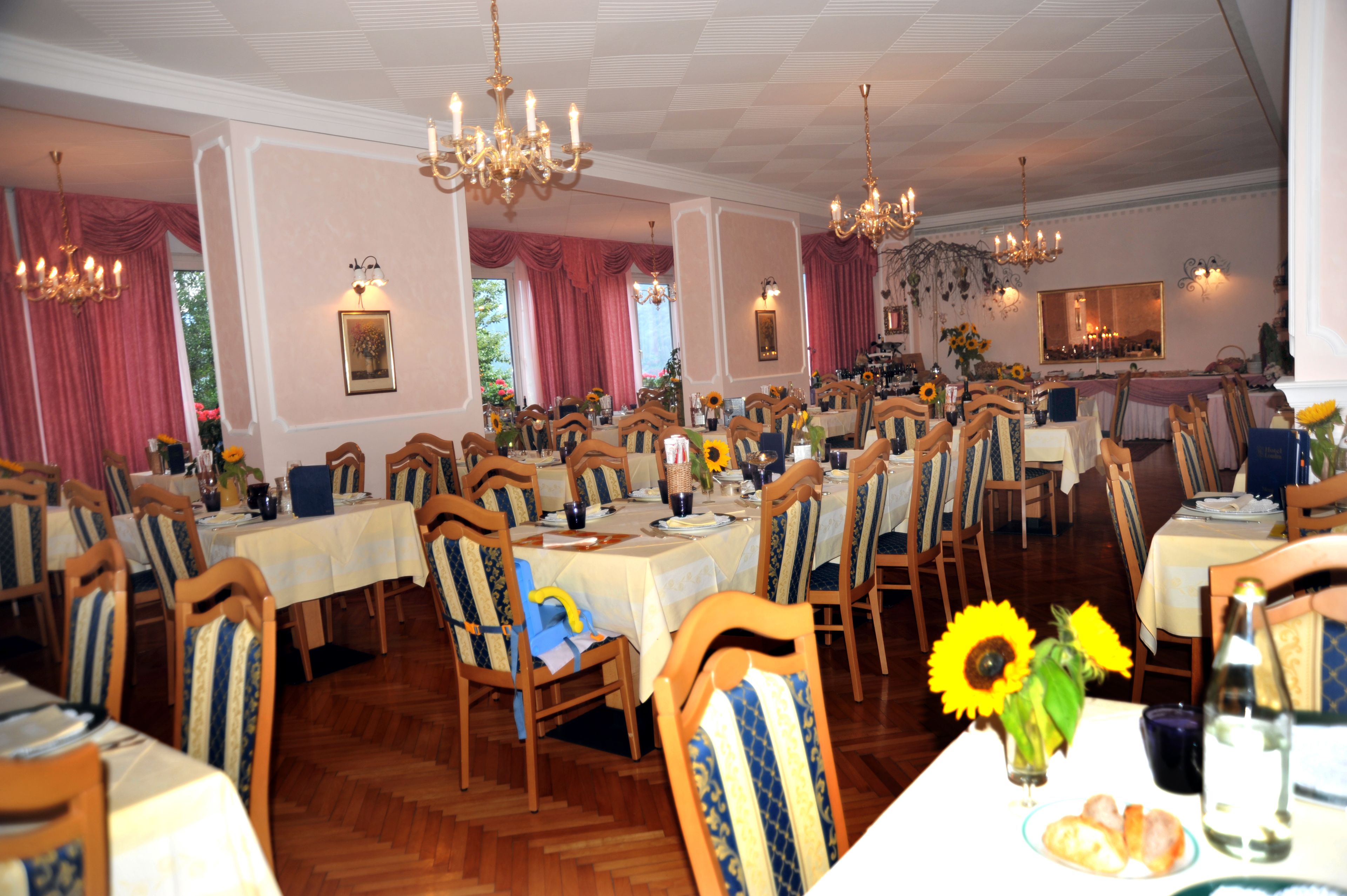 Un comedor con varias mesas y sillas, candelabros y decoración floral.