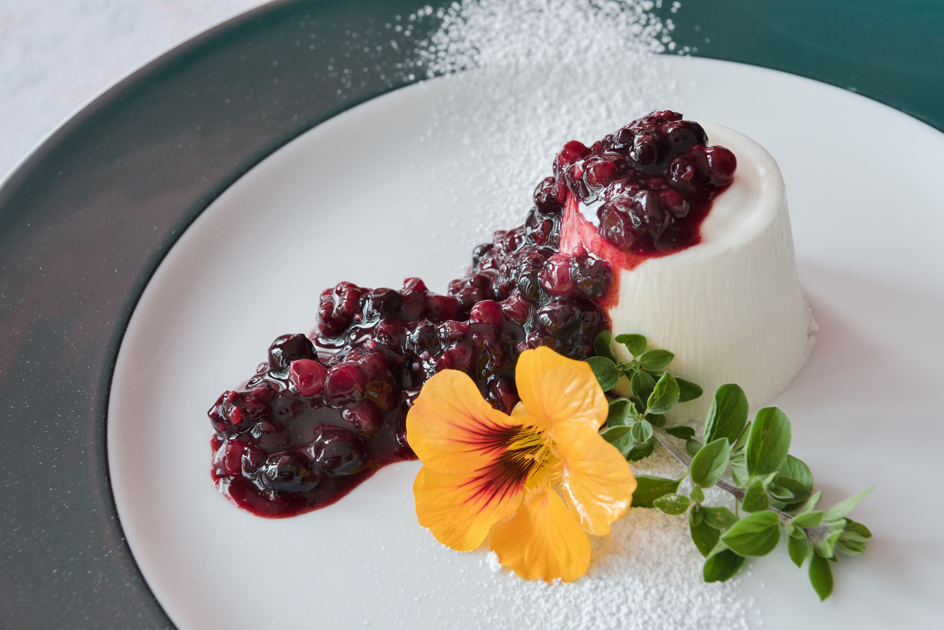 Un postre con bayas y una flor sobre un plato.