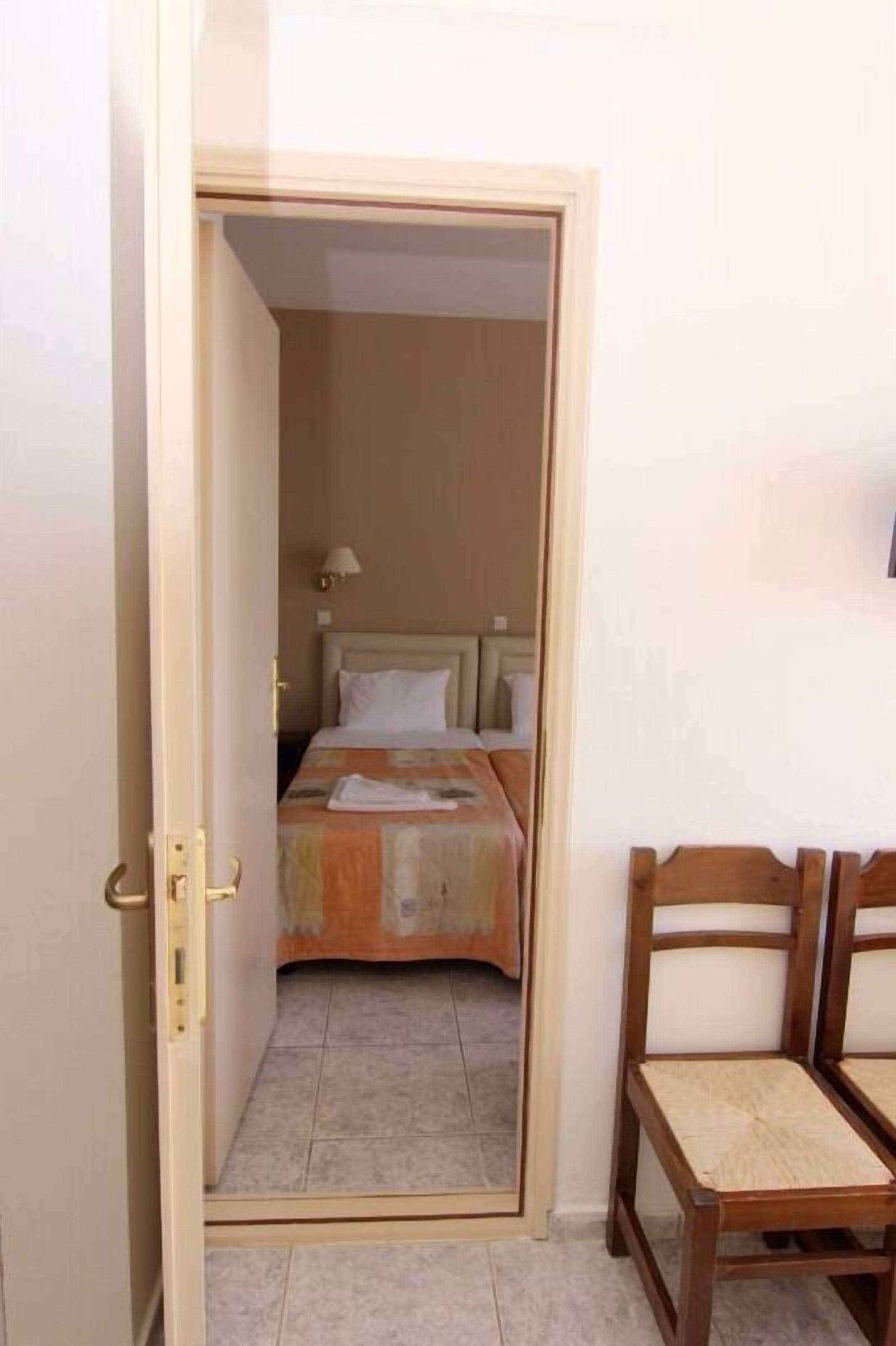 A hotel room with a bed, a chair, and a door.