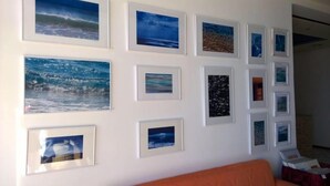 A wall with multiple framed pictures of ocean scenes. - Creta Mare (Agios Vasileios)