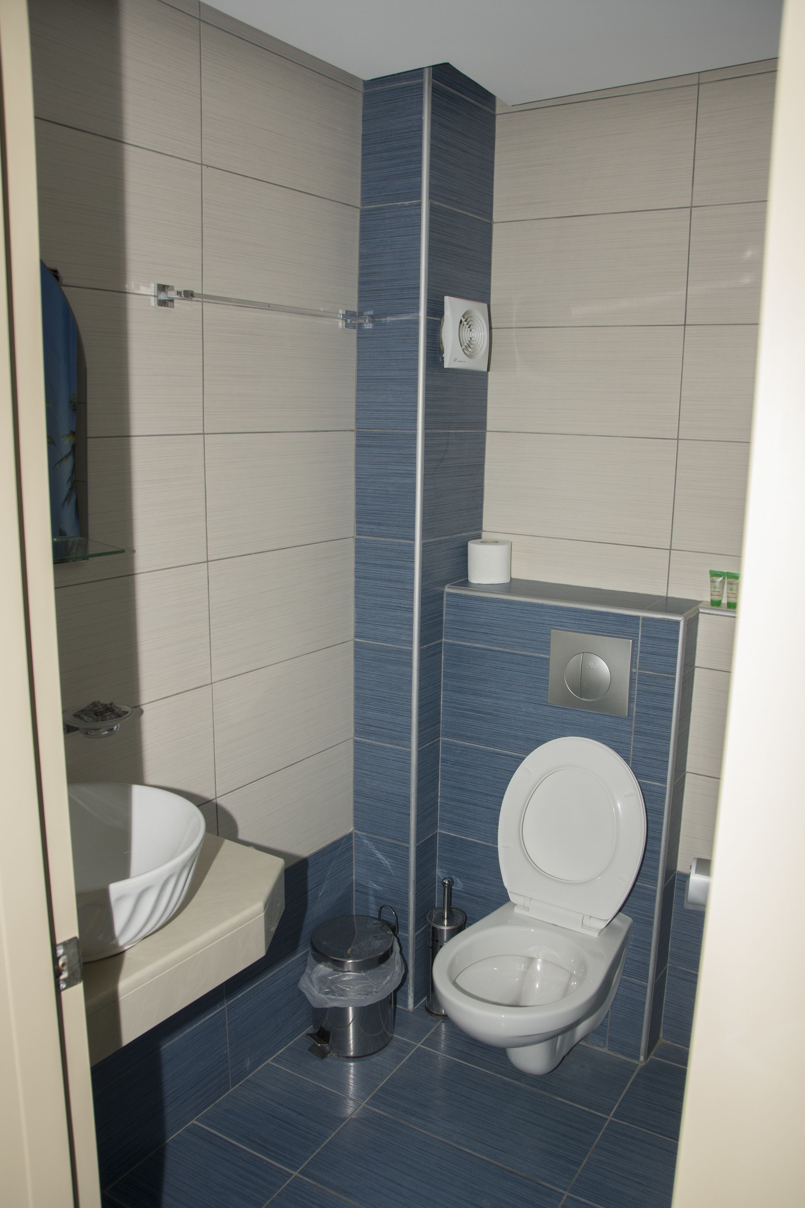 Un baño pequeño con inodoro, lavamanos y toallero.