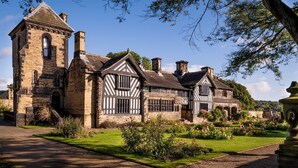 A historic building with a prominent tower, multiple chimneys, and a well-maintained garden with various plants and flowers. - Kirk Lea Guest House (Halifax)
