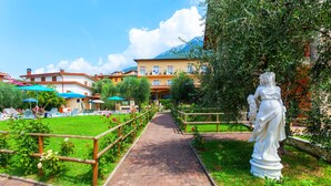 A pathway leading to a building with multiple balconies, surrounded by greenery and a statue. - Villa Isabella Hotel & Residence (Brenzone sul Garda)