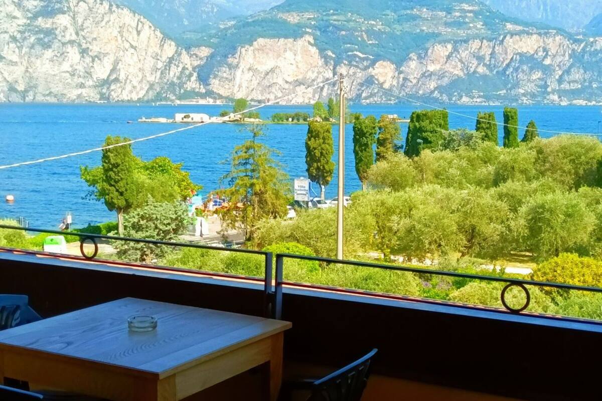 Een balkon met uitzicht op een kustlandschap, inclusief een waterpartij en verre bergen.