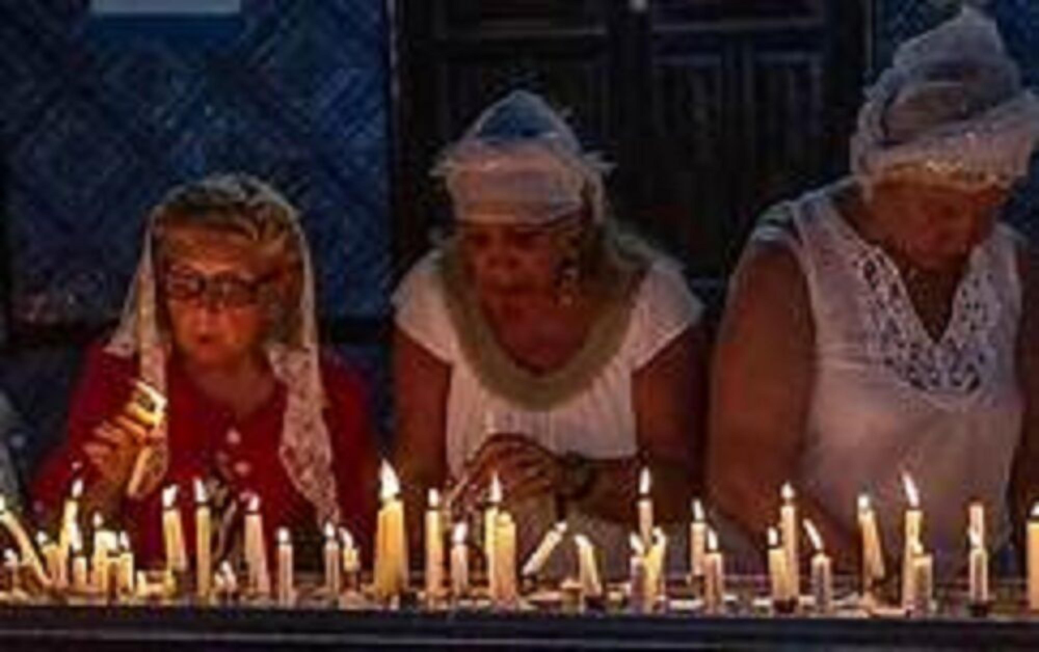 A group of people seated at a table with lit candles in front of them.