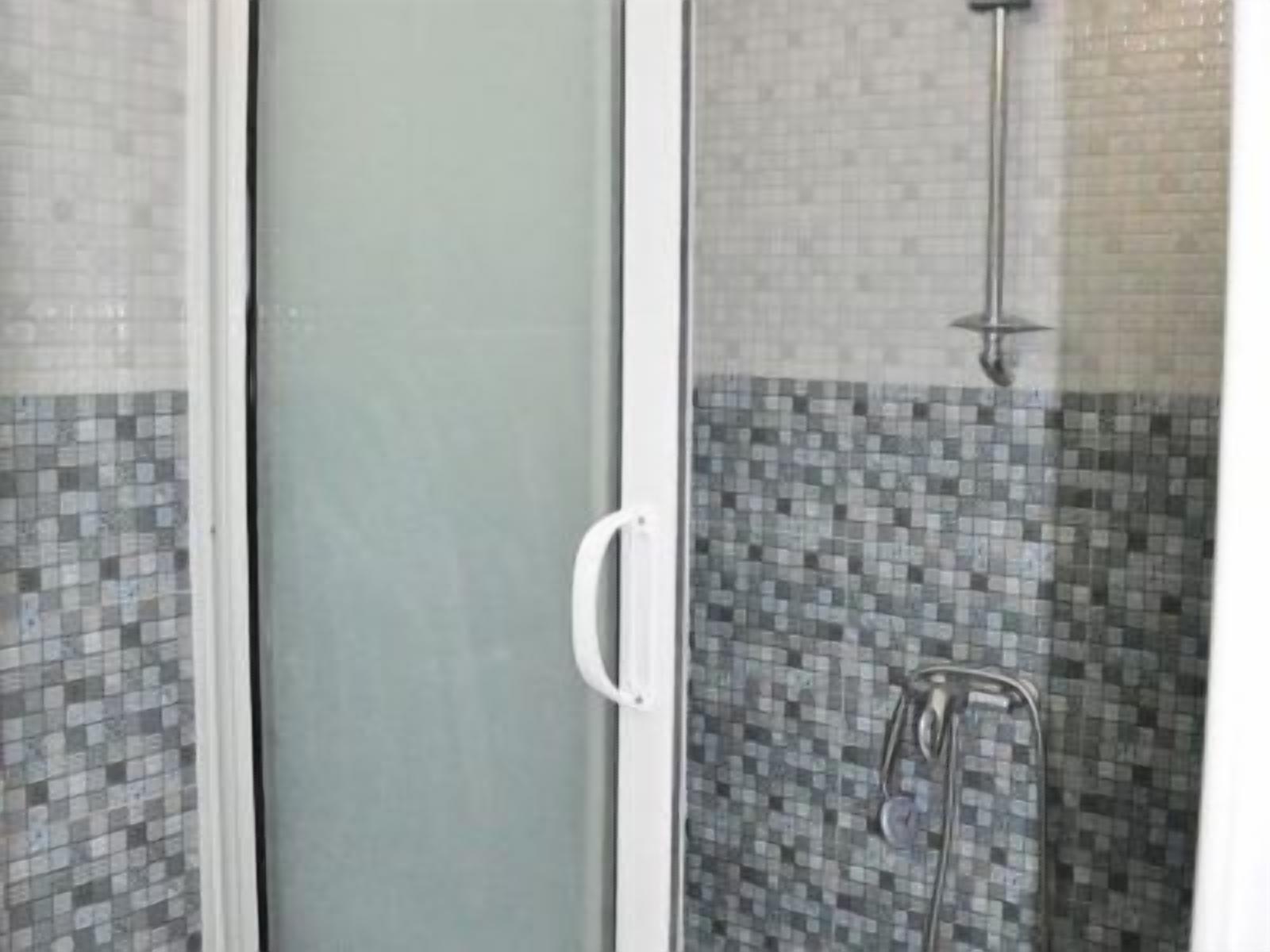 Eine Duschkabine aus Glas mit einer gefliesten Wand und einem weißen Türgriff.