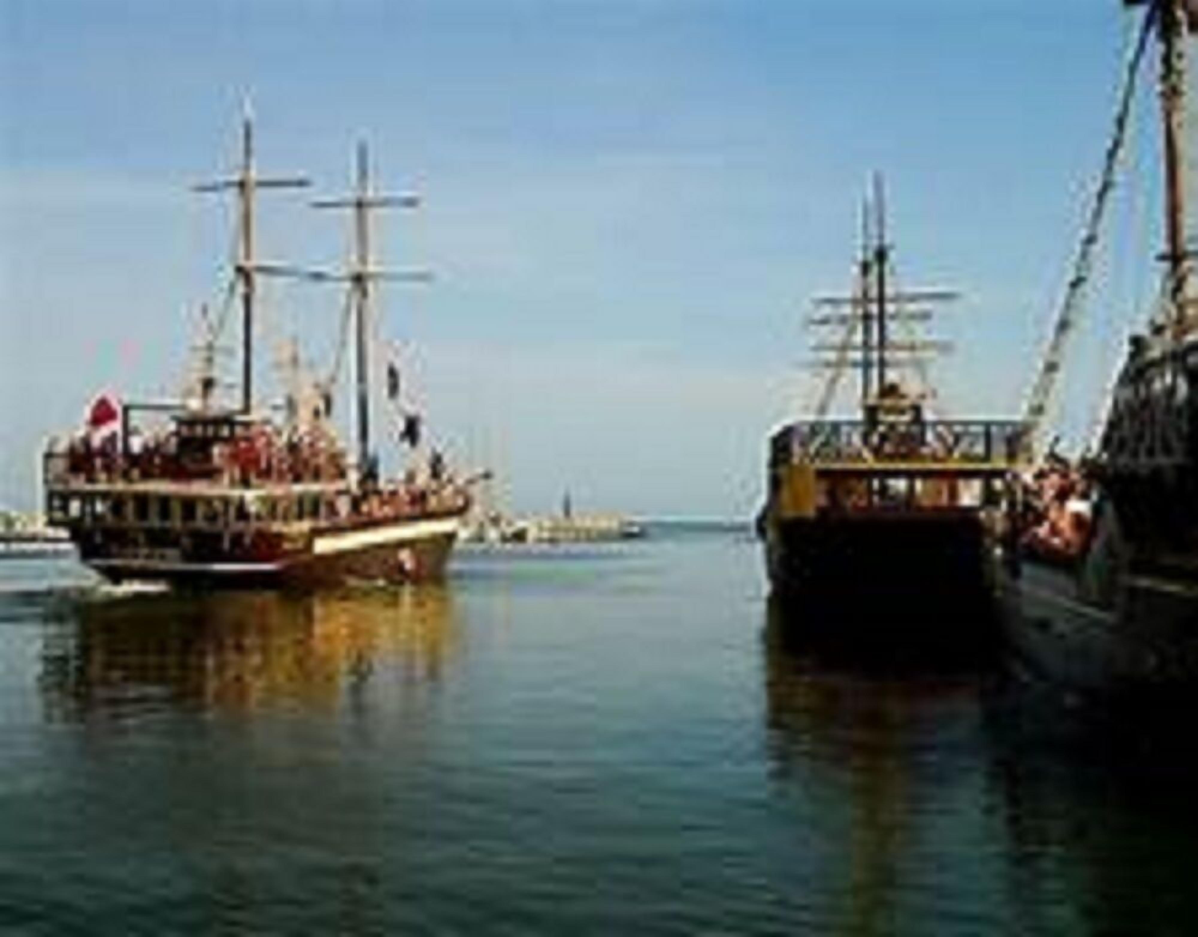 Two large sailing ships docked at a harbor.