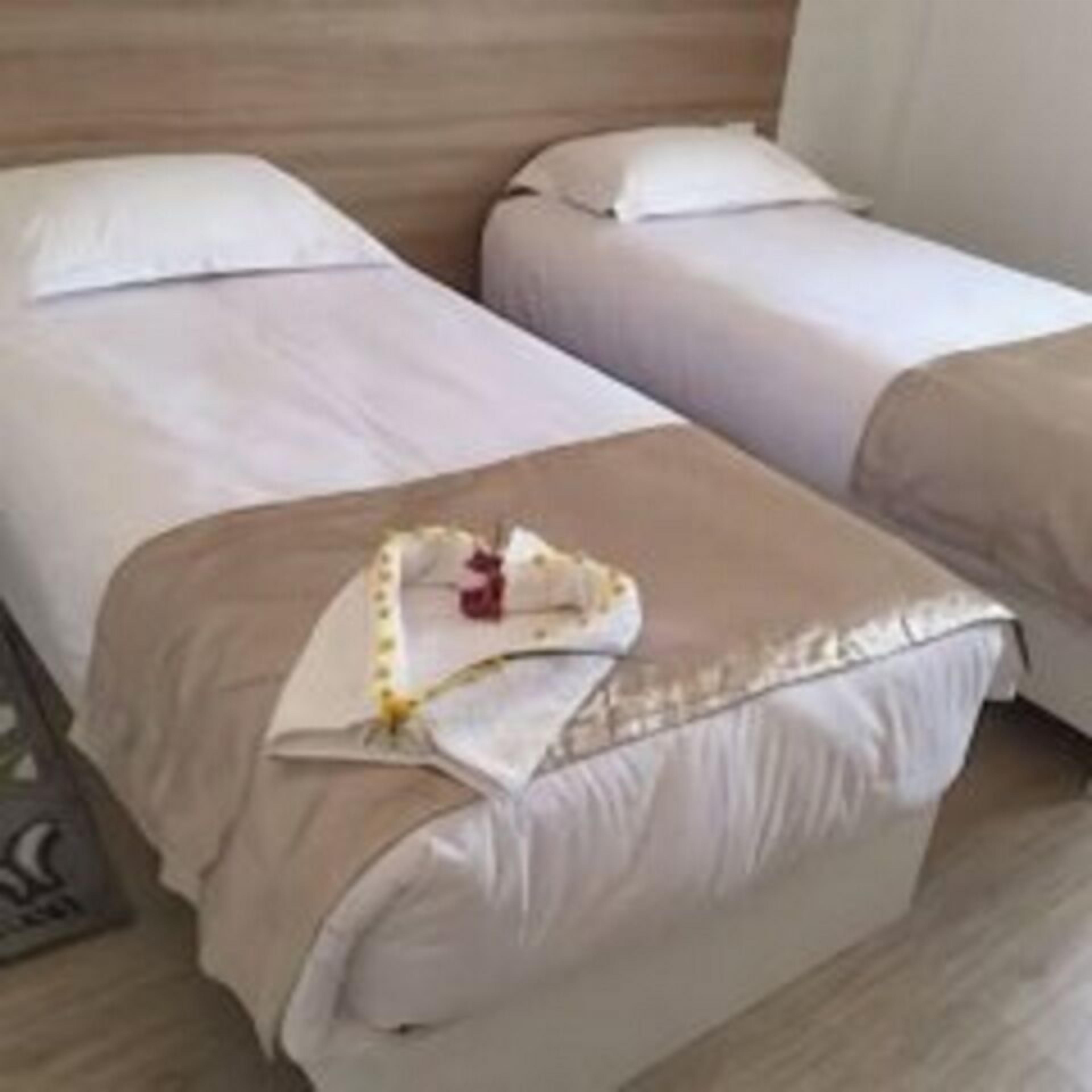 Ein Hotelzimmer mit zwei Einzelbetten, jeweils mit weißer Bettdecke und Kopfkissen.