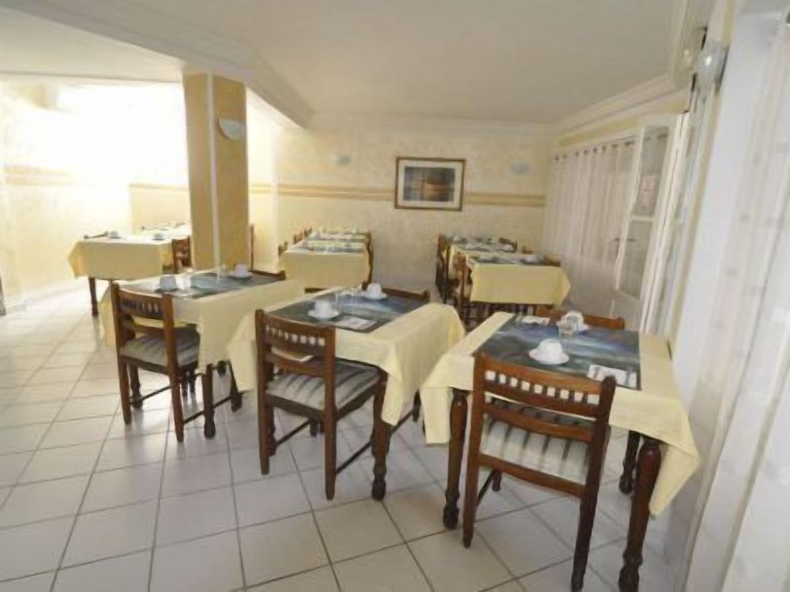 A dining area with multiple tables and chairs, arranged in a spacious room with tiled flooring and light-colored walls.