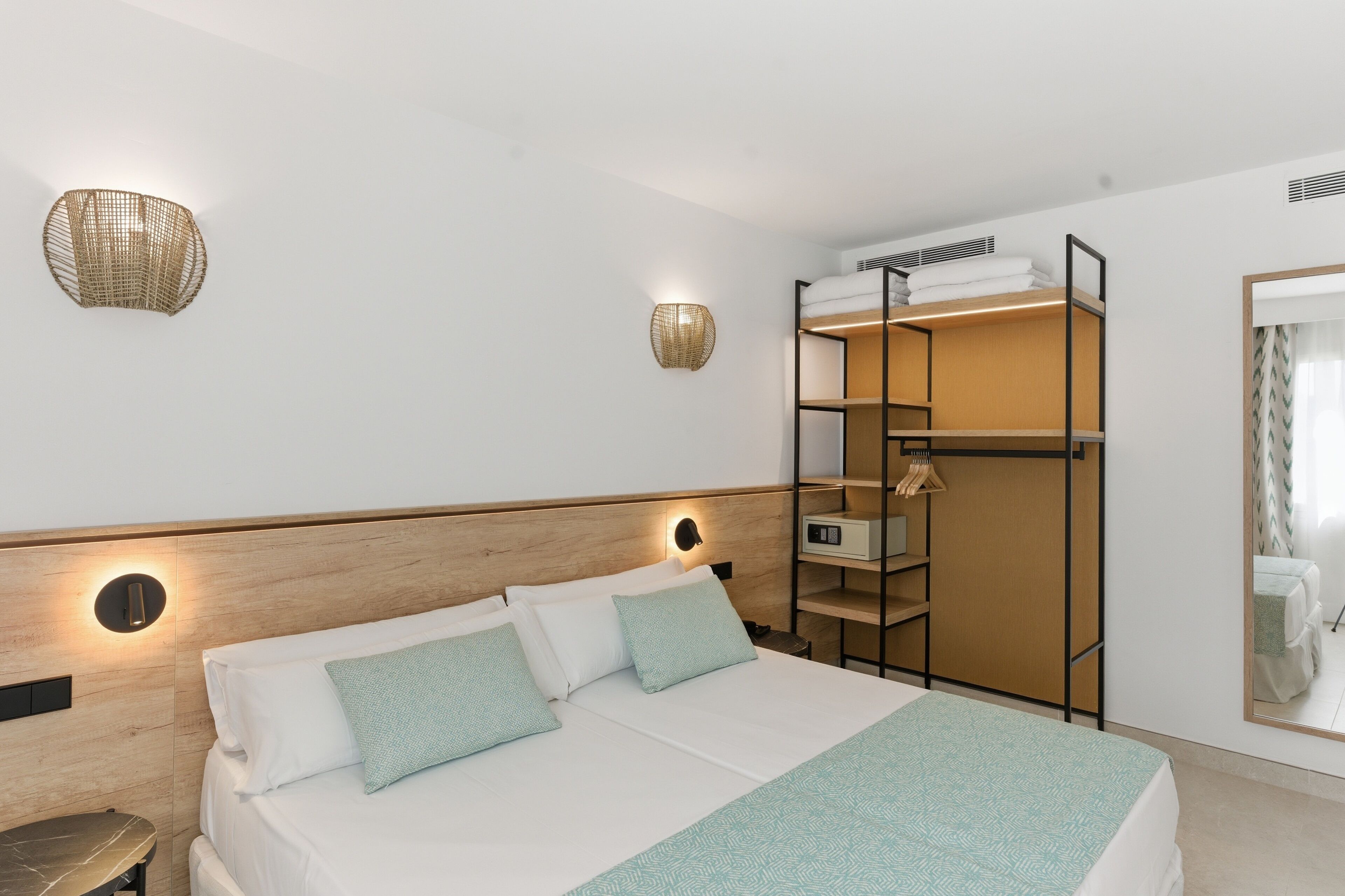 Et hotelværelse med seng, natborde, skab og spejl.