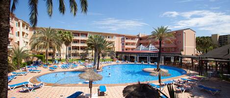 Una piscina al aire libre, sombrillas, sillones reclinables de piscina