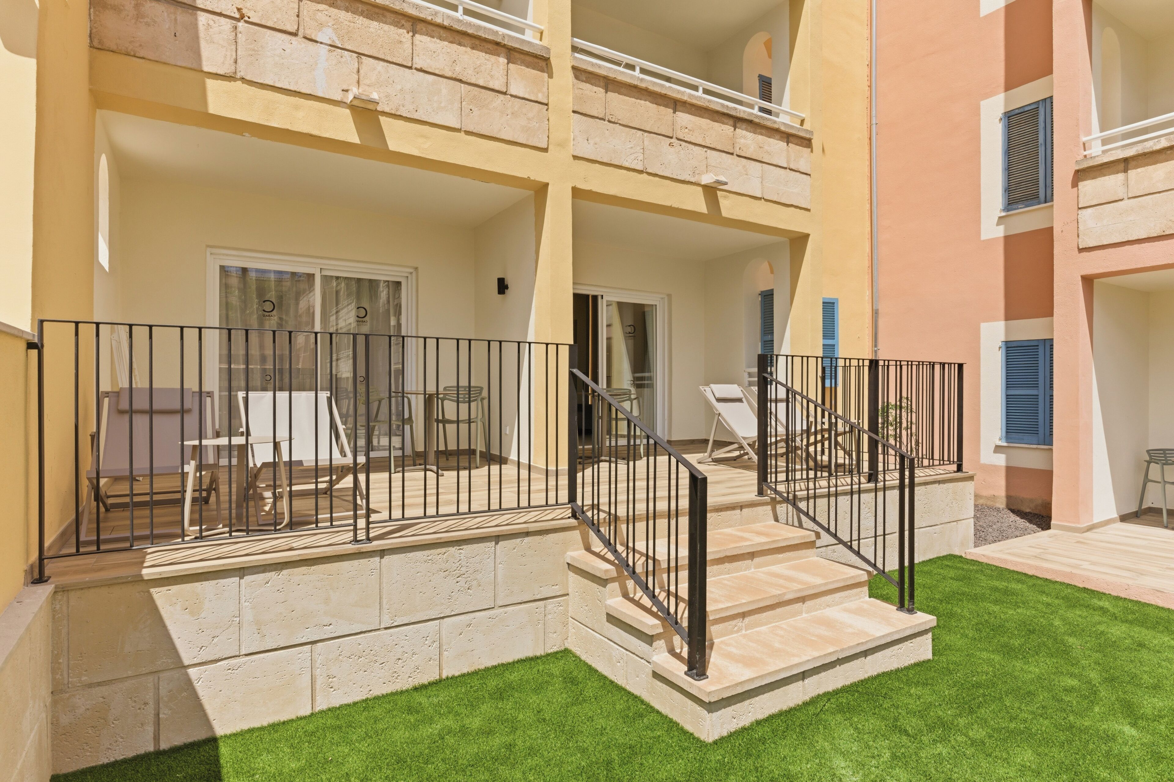 A two-story building with a balcony, outdoor seating, and a staircase leading to the upper floor.