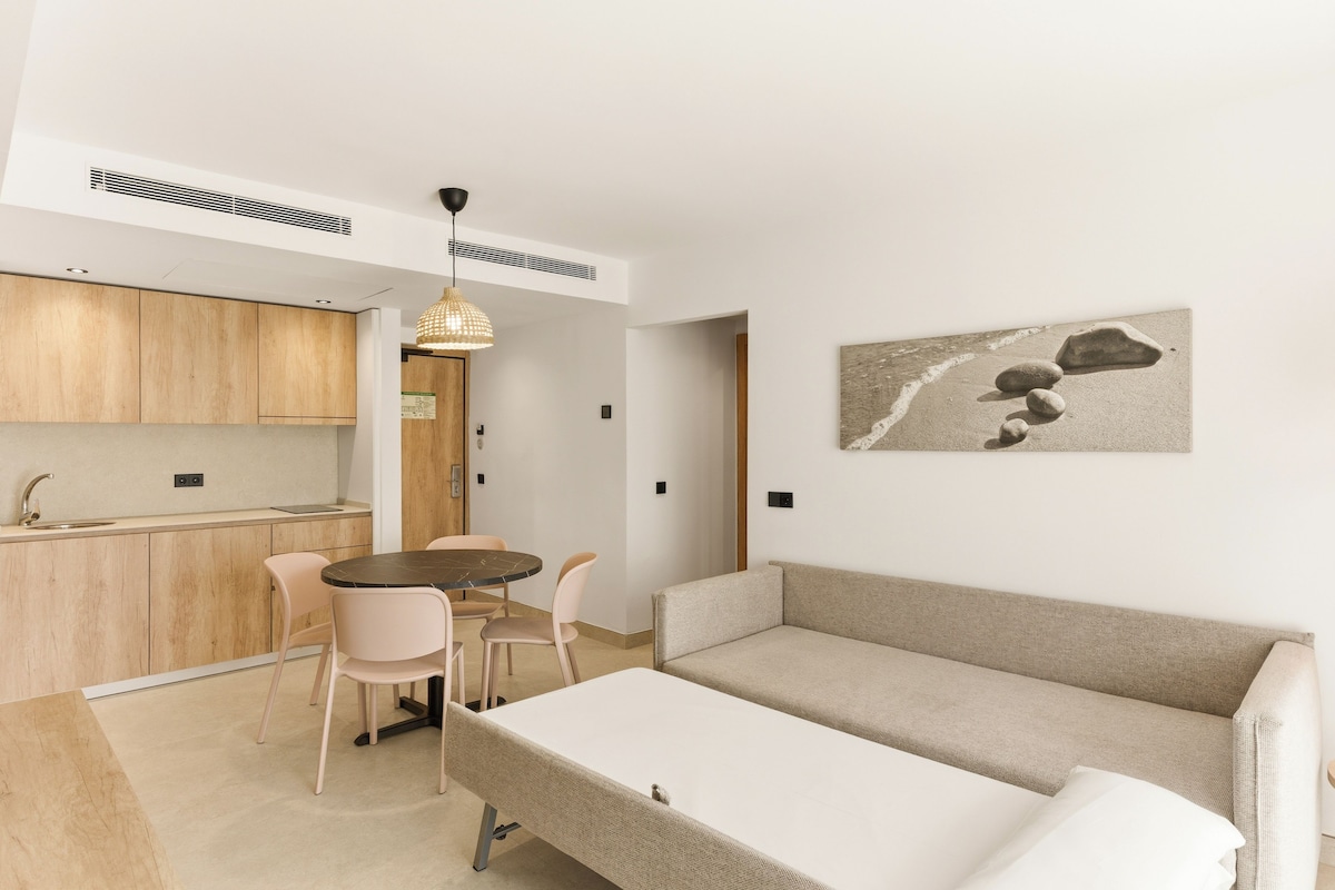 A compact living space with a kitchenette, a dining area, and a sofa.