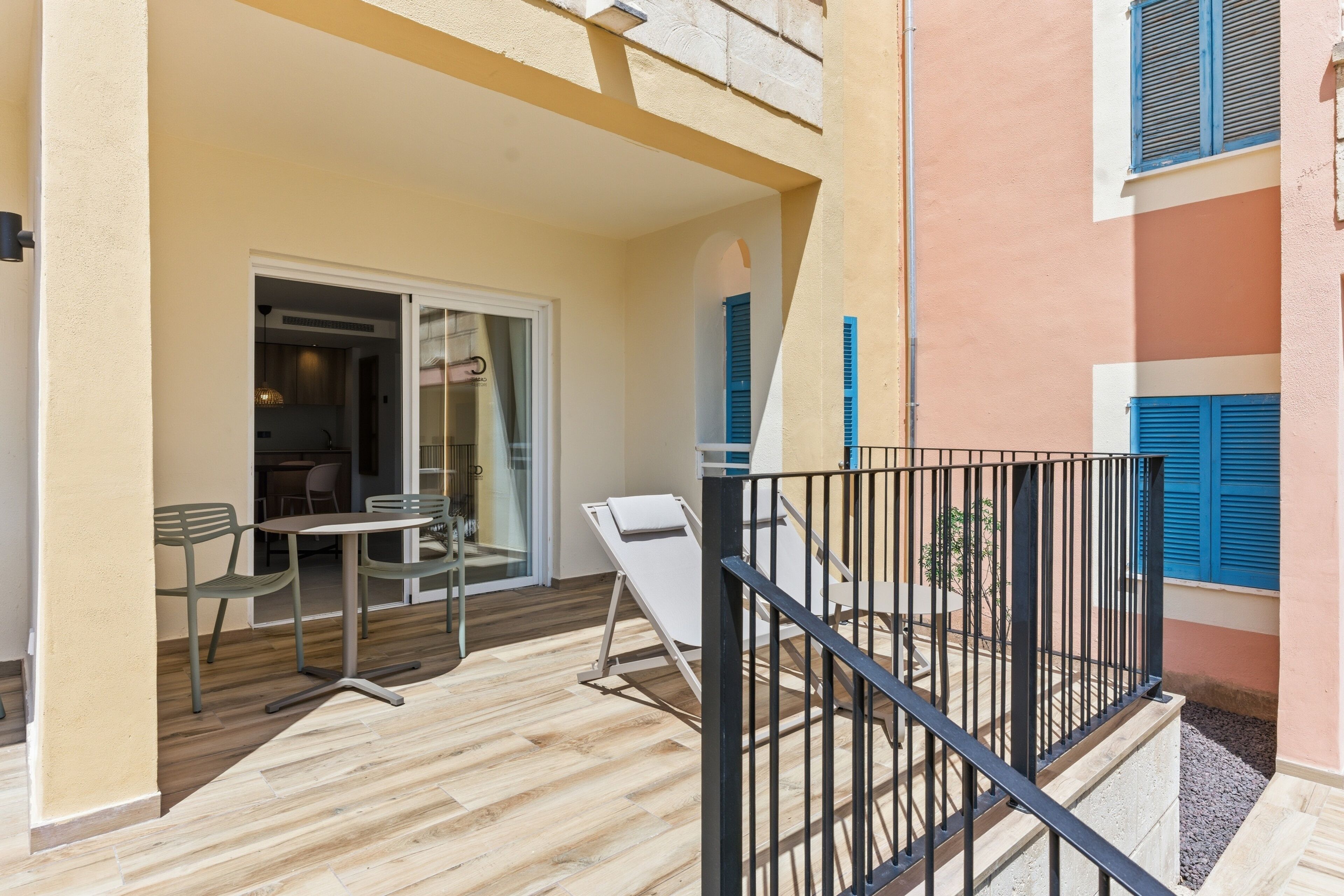 A balcony with a table and chairs, a railing, and a door leading to an interior space.