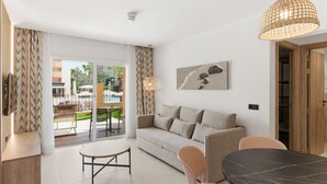 Un salón moderno con sofá, mesa de comedor, sillas, una lámpara colgante y vistas al área exterior.