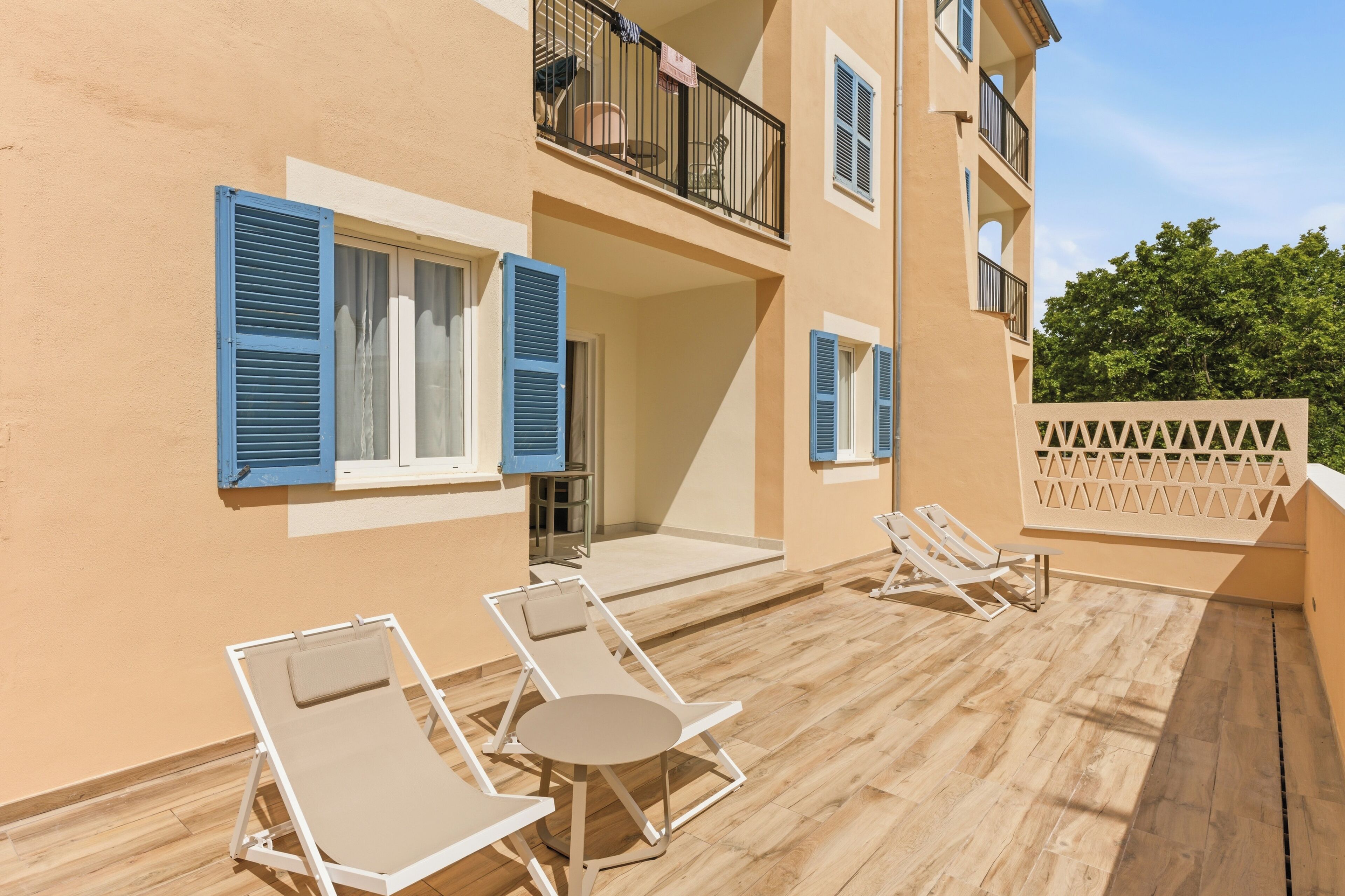 A building with balconies, a wooden deck, and outdoor seating.